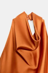 Top de cuello halter satinado en color naranja tostado, con espalda descubierta y cierre trasero de botones.