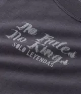 Remera de corte oversized color gris oscuro, con cuello redondo y manga corta. Presenta una estampa gráfica en la espalda que incluye un ángel, estrellas y el lettering 'No Mercy' junto a la frase 'Las calles no perdonan'.