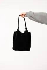 Bolso tote de gamuza color marrón con doble asa de hombro y broche metálico de cierre. Incluye un neceser pequeño.