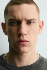 Camiseta de corte slim fit, cuello redondo y manga corta, color gris oscuro con efecto lavado. Presenta un gran estampado frontal con el número "74" en blanco desgastado y pequeños estampados circulares en los hombros.