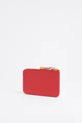 Monedero de piel vacuna con estructura blanda, cierre de cremallera con tirador de cordón y logo metálico frontal. Cuenta con bolsillo interior y placa metálica logotipada.