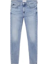 Jeans de mezclilla azul claro, tiro medio, con corte slim que se estrecha hacia el tobillo. Presentan un diseño de cinco bolsillos, bragueta con cremallera y herrajes de Calvin Klein, incluyendo una insignia de cuero en la parte trasera.