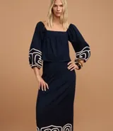 Pollera recta de largo midi en color azul marino, confeccionada en tejido de cambraia de algodón y lino. Presenta un bordado geométrico en color crema en el ruedo, cierre de cremallera y abertura central en la parte trasera.