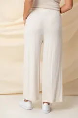 Pantalón ancho color beige, de hilo, con cintura elastizada ajustable con cordón y bolsillos laterales.