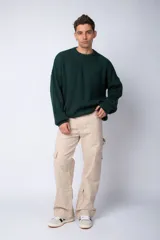 Pantalón tipo carpintero de corte relaxed fit y tiro medio, confeccionado en denim negro con costuras a contracolor en blanco. Presenta múltiples bolsillos cargo laterales, un bolsillo con cierre en la parte inferior y presillas utilitarias.