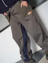 Pantalón de neopreno impermeable forrado de polar, de corte holgado, color verde militar con paneles laterales en azul marino, bolsillos con cierre y parche de cuero sintético con logo.