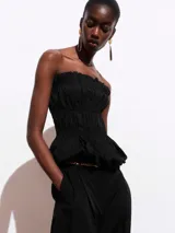 Top negro strapless con cuerpo fruncido tipo smock y bajo abullonado con acabado peplum.