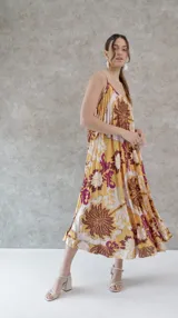 Vestido largo de seda plisada estampada con flores grandes en tonos marrón, amarillo y violeta. Diseño de solera con tirantes finos.