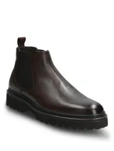 Botín tipo Chelsea de cuero color marrón oscuro, con paneles laterales elásticos y suela de goma dentada. Diseño clásico con tirador trasero.