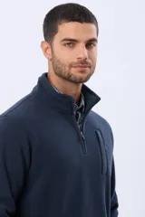 Buzo polar de abrigo en color verde oscuro, con cuello alto y medio cierre frontal. Presenta un bolsillo vertical en el pecho y bolsillos laterales, ideal para climas fríos.