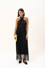 Vestido midi de satén color negro, con escote halter cruzado y ruedo terminado en flecos largos.