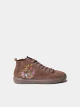 Botín de cuero serraje color beige, con cordones y detalle de flores bordadas en el lateral. Cuenta con suela plana de goma y cierre de cremallera lateral.