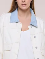 Campera de denim blanco de corte holgado con hombros caídos, cuello con solapa en contraste de color celeste, cierre frontal con botones metálicos y bolsillos delanteros con solapa.