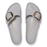 Sandalias Birkenstock modelo Madrid Big Buckle, color gris claro con acabado brillante. Presentan una tira ancha ajustable con una hebilla metálica grande en tono dorado. La base es de corcho natural con plantilla anatómica y suela de goma negra.