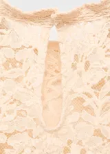 Blusa de gasa color beige claro, con cuello redondo, mangas largas abullonadas, panel frontal superior de encaje y diseño evasé con volados en el ruedo.