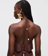 Blusa halter color marrón de viscosa, con diseño sin mangas, cuello halter con atadura posterior y estampa tropical inspirada en pañuelo con detalles en tonos dorados y naranjas.