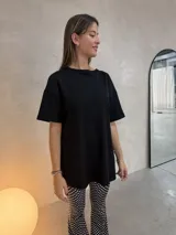 Conjunto compuesto por un remerón negro de corte holgado con aberturas laterales y un pantalón de tiro alto con diseño acampanado y estampado de lunares blancos sobre fondo negro.