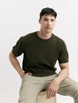 Remera de punto color beige, de manga corta y cuello redondo.