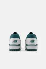 Championes urbanos New Balance modelo 550, con diseño retro inspirado en el básquet, combinando cuero blanco con detalles en gamuza gris y acentos en color verde oscuro.