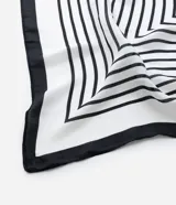 Pañuelo cuadrado de satén con estampado geométrico de líneas concéntricas en blanco y negro. Presenta un borde negro sólido y acabado brillante.