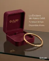Pulsera esclava rígida de acero con baño de oro, compuesta por eslabones cilíndricos unidos entre sí.
