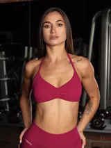 Set deportivo sin costuras color fucsia compuesto por un top bra con escote halter y espalda descubierta, y una calza legging con control de abdomen y realce de glúteos.