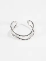 Pulsera tipo cuff rígida de metal plateado, con diseño de doble aro abierto.