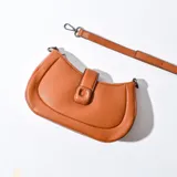 Bandolera marrón de cuero sintético con correa ajustable.
