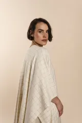 Ruana de lana fina color crudo con terminación envivada.