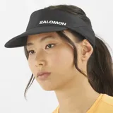 Visera deportiva Salomon modelo SHAKEout, de color negro con el logotipo de la marca impreso en blanco en el frente. Diseño transpirable y de secado rápido, ideal para running y actividades aeróbicas.