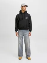 Buzo con capucha y manga larga, fit holgado, color negro. Confeccionado en tejido de punto circular loopback 100% algodón con interior cepillado. Presenta un estampado ovalado en la espalda con texto en blanco que incluye "ESTABLISHED IN COPENHAGEN 1990", "JACK&JONES WORLDWIDE MRK", "ORIGINALS CREATIVE DEPARTMENT DAILY BASICS" y "FROM VISION TO REALITY".