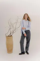 Pantalón sastrero de tiro medio, color gris oscuro con rayas verticales finas. Presenta pinzas delanteras, bolsillos delanteros con pin bordado y bolsillos traseros tipo vivo.