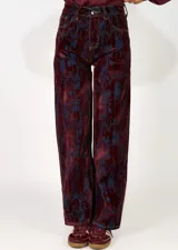 Pantalon de corte recto confeccionado en denim con un acabado desgastado en tonos bordó y azul oscuro. Presenta diseño de cinco bolsillos, cierre frontal con botón y costuras a contratono.