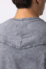 Remera de corte oversize con efecto de lavado gastado, confeccionada en algodón pesado. Presenta cuello redondo, mangas cortas con costuras visibles y un diseño amplio.