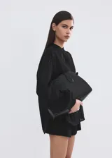 Blusa Lucy de diseño recto color negro, confeccionada en mezcla de algodón y viscosa. Cuenta con cuello mao, detalles bordados calados, manga larga y cierre frontal con botones.