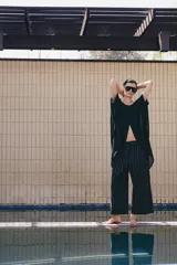 Pantalón de tiro medio confeccionado en mezcla de lino, con diseño de rayas verticales. Presenta cintura con trabillas, bolsillos laterales, pinzas en el delantero y cierre frontal con cremallera y botón.