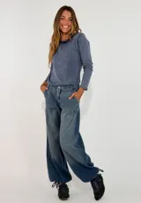 Pantalon de jean estilo wide leg con diseño de tiro medio, bolsillos laterales y detalle de costura horizontal a la altura de la cadera que genera un efecto de volado sutil.