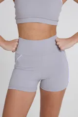 Minishort deportivo gris con cintura alta y recortes laterales blancos.