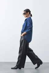 Pantalón de cuero sintético con fit barrel, de silueta amplia con volumen en las piernas y botamanga levemente entallada. Presenta bolsillos laterales y cierre frontal.