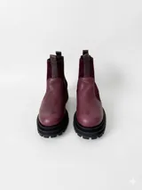 Botas tipo chelsea de cuero, combinando texturas en color bordó. Presentan paneles laterales elásticos en negro, suela track robusta y tiradores en la parte superior.