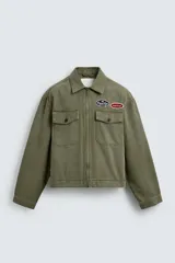 Cazadora cropped de algodón con efecto lavado, color verde militar. Presenta cuello solapa, cierre frontal con cremallera, bolsillos frontales de plastrón con solapa y parches decorativos en el pecho.