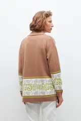 Ruana color tostado con guarda jacquard floral en mangas y bolsillos.