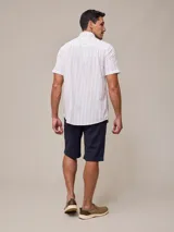 Camisa de manga corta para hombre, color blanco con rayas verticales finas en relieve. Tiene cuello abotonado, bolsillo en el pecho izquierdo y logo bordado pequeño.