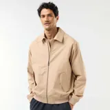 Campera de twill beige con cierre frontal, cuello camisero, bolsillos laterales con solapa y puños y cintura elastizados de rib.