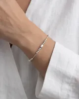Pulsera de plata 925 fina y delicada con eslabones de cadena y abalorios de cuentas esféricas de diferentes tamaños y un dije central ovalado liso.