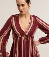 Vestido largo evasé de Marfinno, confeccionado en mezcla de viscosa y lino, con diseño de rayas verticales en tonos bordó y beige. Presenta escote en V, busto ajustado y mangas largas abullonadas con puños elastizados.