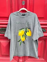 Remera oversize de algodón con efecto gastado (acid wash) color gris, con estampa frontal que incluye la palabra "amalfi" en cursiva verde y un racimo de limones amarillos con hojas verdes.