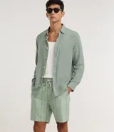 Bermuda de playa para hombre, de corte recto y color verde menta, confeccionada en algodón texturizado con diseño de rayas sutiles. Cuenta con cintura elástica con cordón de ajuste, bolsillos laterales y diseño sin estampas.
