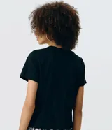 Remera negra de algodón con cuello redondo, manga corta y bordado frontal en relieve con forma de mariposa.