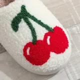 Pantuflas blancas con interior de felpa y estampado de cerezas rojas con hojas verdes.